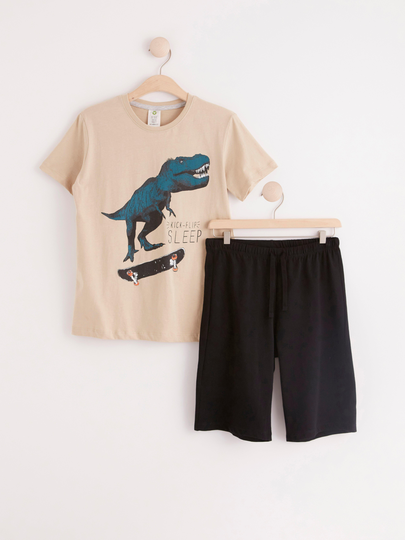 Pyjamasset med en dinosaurie på en skateboard